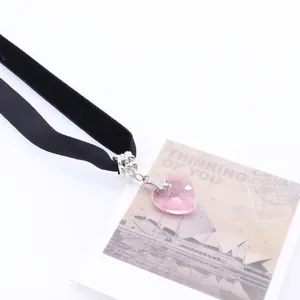 Detail of pink crystal heart pendant on black velvet choker necklace with soft texture
