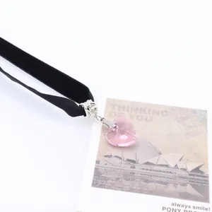 Macro detail of a black velvet choker featuring a faceted pink heart crystal pendant