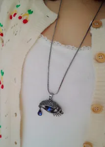 Dettaglio del ciondolo a forma di occhio con goccia di cristallo blu e catena in argento