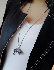 Dettaglio di una collana lunga con pendente a forma di occhio di cristallo e goccia blu