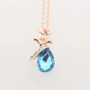Dettaglio collana in oro rosa con pendente a rosa e cristallo blu a forma di goccia