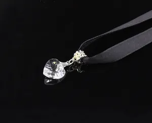 Detailed macro view of heart crystal pendant with black ribbon on reflective surface