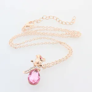Dettaglio macro di una collana in oro rosa con cristallo a goccia rosa e rosa decorata