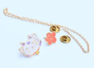 Detalle del set de broches esmaltados gato de la suerte con flor naranja y cadena