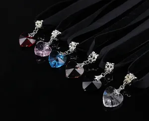 Macro shot of colorful heart crystal pendants on black velvet chokers with glossy reflections