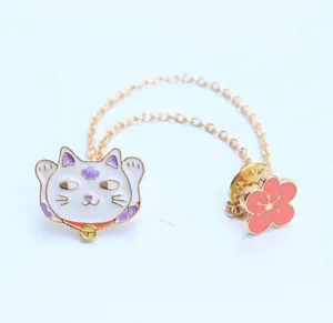 Detalle de broche de esmalte de gato de la suerte y cerezo con doble cadena dorada