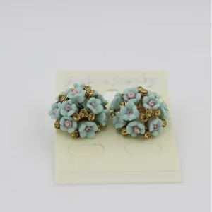 Fashionable floral earrings featuring light blue and pink ceramic flowers with crystals