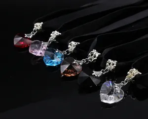 Detail view of heart-shaped crystal pendants on black velvet choker necklaces in various colors