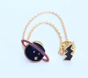 Detalle de broche de doble cadena con colgantes de esmalte de planeta y rayo dorado