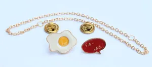 Detalle del set de broches esmaltados de huevo frito y 'Eat Well' con cadena dorada