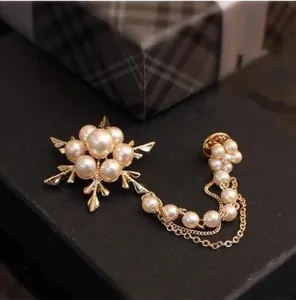 Détail macro d'une broche flocon de neige dorée avec perles et double chaîne de connexion