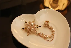Détail d'une broche flocon de neige dorée avec perles et chaînes sur plateau en cœur