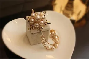 Détail macro d'une broche flocon dorée avec perles et élégants pompons pendants