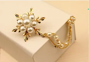Élégante broche flocon de neige en perles dorées avec chaîne sur une boîte à bijoux blanche