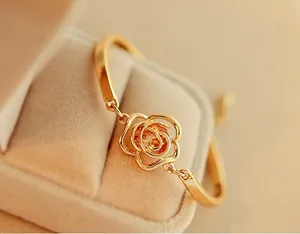 Detailed view of hollow rose gold bracelet with an orange crystal on a beige jewelry box