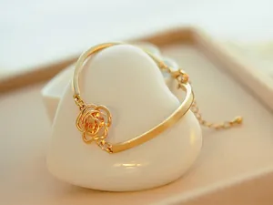 Detail of gold hollow rose bracelet with champagne crystal on white heart-shaped stand