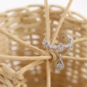 Detalle de ear cuff plateado con flores de diamante y colgante de gota de agua brillante