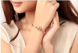 Detail of rose gold bangle featuring hollow flower design on a female model wrist
