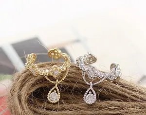 Detalle de clips de oreja en oro y plata con circonitas de gota y patrones calados