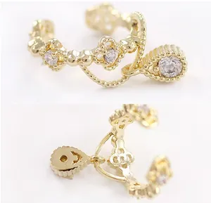 Detalle de un pendiente de clip dorado con piedras de circonita cúbica en forma de pera