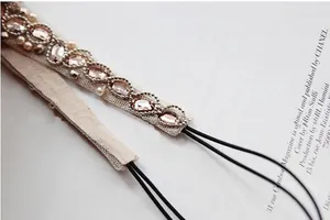 Macro detail of handmade bridal headband with pink crystals, white pearls and lace