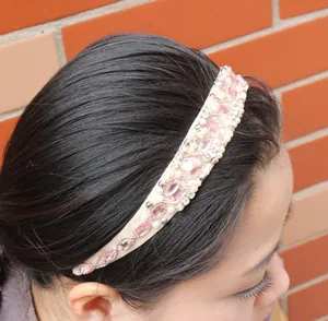Detail view of handmade pink crystal and pearl headband worn by a female model