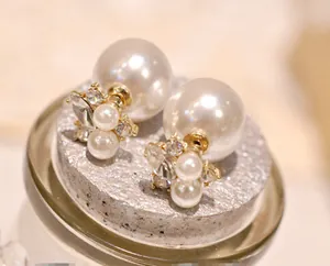 Macro detail of elegant double-sided pearl earrings with crystal flower cluster