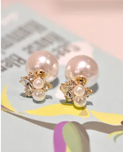 Macro shot of double-sided pearl earrings with crystal star flower in gold finish