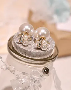 Macro shot of double-sided pearl earrings with clear rhinestones on gold metal base