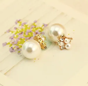 Close-up of double-sided stud earrings with white faux pearls and shiny rhinestones