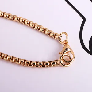 Gros plan d'un collier chaîne box en or avec finition polie et fermoir mousqueton
