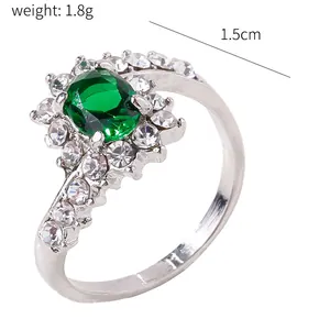 Macro view of silver-toned ring featuring an oval green gemstone and crystal accents