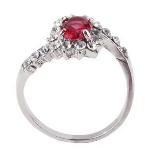 Close-up of elegant silver ring featuring oval red gemstone and pavé crystal accents