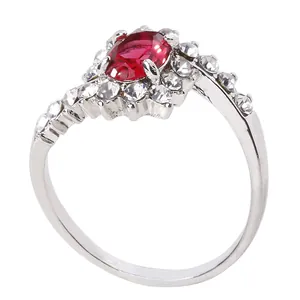Detailed close-up of a silver ring featuring an oval red gemstone and asymmetrical diamonds