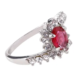 Macro shot of oval red gemstone ring with side crown diamond setting on silver band