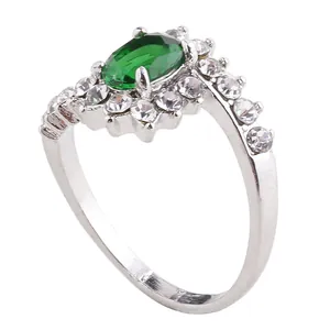 Elegant silver ring with oval green gemstone and diamond-like halo on white background