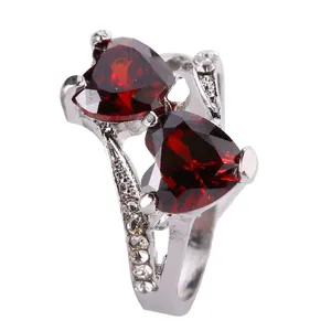Detail of silver ring featuring dual heart-cut deep red crystals and pavé accents