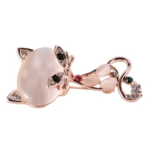 Broche chat en or rose avec opale et strass scintillants sur un fond blanc neutre