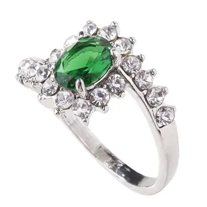 Macro view of silver ring featuring oval green gemstone surrounded by sparkling white crystals