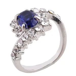 Macro detail of silver ring with oval blue gemstone and surrounding white zircon accents