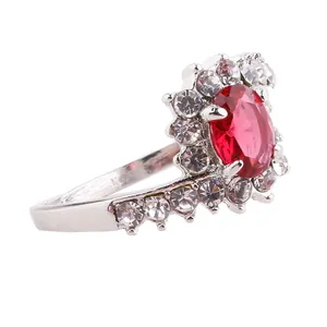 Macro view of halo oval red gemstone ring with small sparkling diamonds on silver band