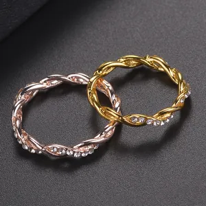 Pair of gold and rose gold twisted rope rings with pave-set rhinestones on a leather background
