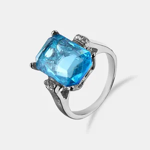 Elegant emerald cut light blue crystal ring with side diamond accents in silver finish