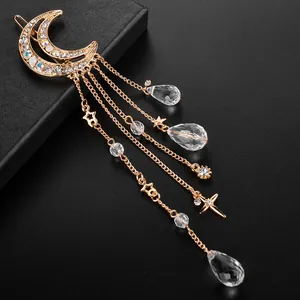 Elegante pasador de luna dorada con pedrería brillante y cadenas largas de borlas