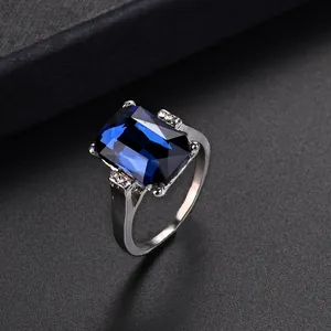 Macro shot of rectangular blue crystal ring with side diamond accents in silver finish