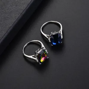 Close-up of rectangular sapphire blue and aurora crystal rings with diamond accents