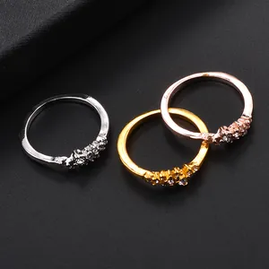 Tre anelli sottili in argento, oro e oro rosa con zirconi incastonati su sfondo scuro