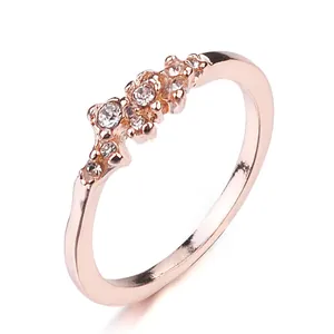 Macro primo piano dell'anello in oro rosa con nove cristalli trasparenti su fondo bianco