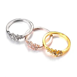 Dettaglio di tre anelli in argento, oro e oro rosa con cristalli incastonati su sfondo bianco