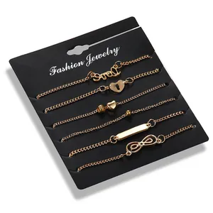 Set of 6 gold alloy ankle bracelets with heart, infinity, and cool charms on card